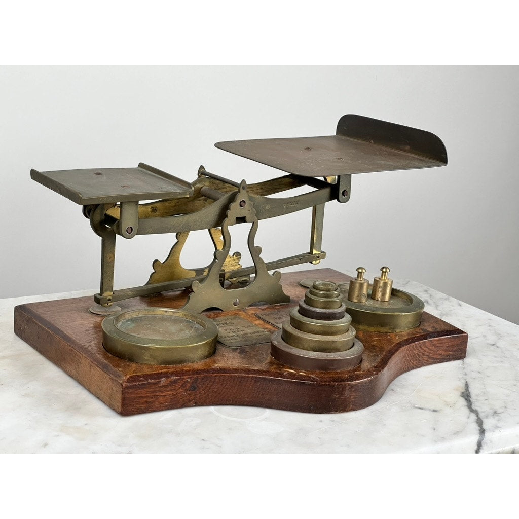 The Antique 19th Century English Postal Scale, with a wooden base, twin metal pans, and graduated brass weights, is displayed on marble—a fine example of elegant Victorian scientific instruments. Brand: Unknown.
