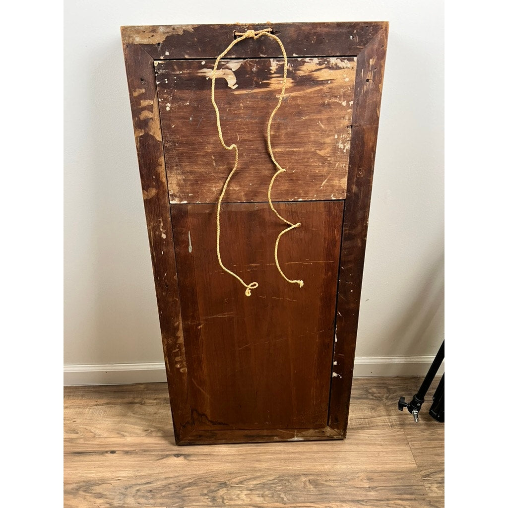 An Antique Federal Period Giltwood Mirror with Rosette Corners and Cornucopia c. 1830, showing scratches and a hanging wire, leans against a white wall on a wooden floor—suggesting its rich history and classic design.
