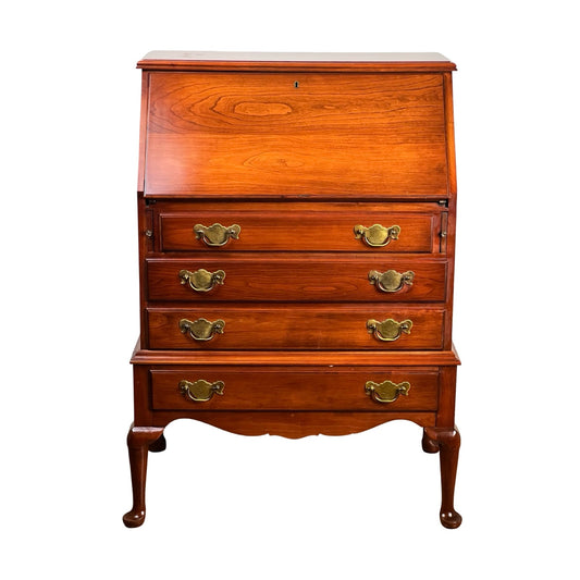 The Vintage Solid Cherry Queen Anne Style Slant Front Secretary Desk by Pennsylvania House features a hinged writing surface, four drawers with ornate brass handles, and elegant Queen Anne curved legs.