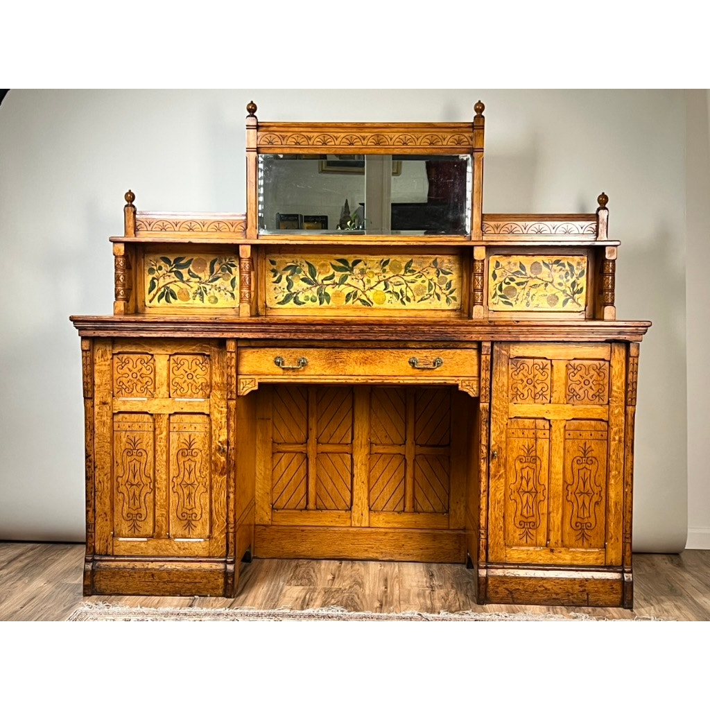 An Antique Victorian Aesthetic Movement Oak Desk in original finish c. late 19th century, featuring ornate carvings, a central mirror, floral tile panels, two cabinets, and a drawer—evoking classic period elegance.