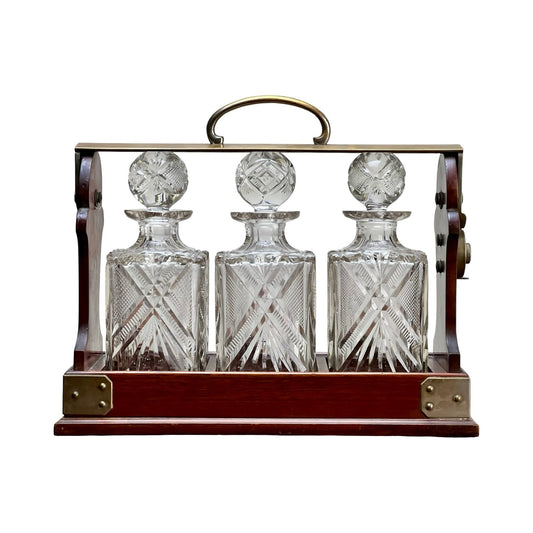 This Antique English Edwardian Betjemann’s Cut Crystal Three Bottle Tantalus (c. early 20th century) features three ornate crystal decanters with stoppers in a handled Betjemann’s case, each boasting intricate cut patterns.