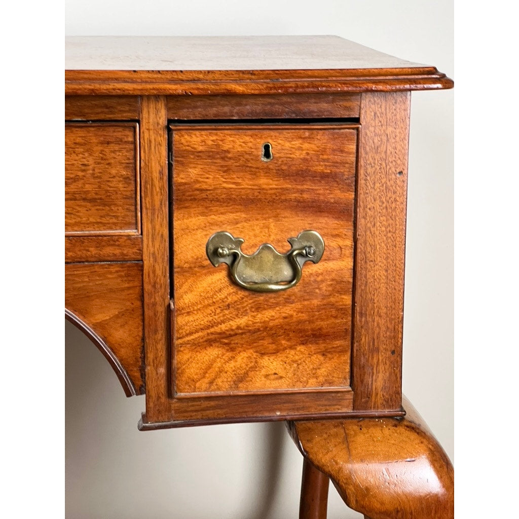 Close-up of an Antique George III Queen Anne Mahogany Lowboy (Late 18th Century) drawer featuring a brass handle, keyhole, and rich wood grain; part of a matching wooden chair is visible below. Brand: Unknown.