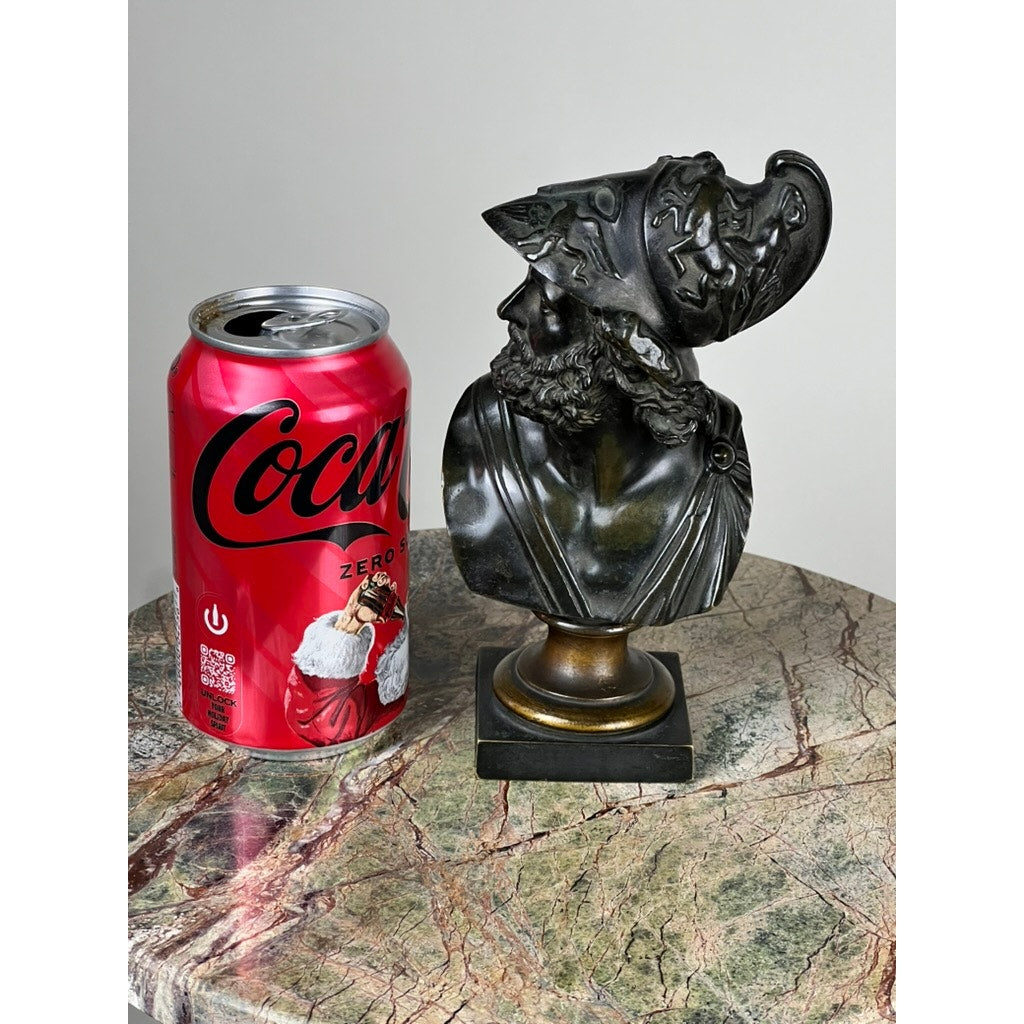A red Coca-Cola Zero can and an antique small bronze bust of King Menelaus (late 19th century) rest side by side on a polished, multicolored marble surface.