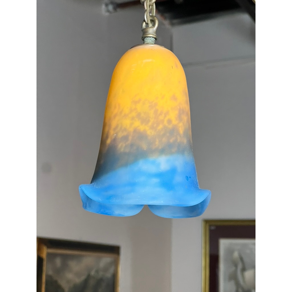 A Vintage Muller Frères Lunéville French brass and art glass four-light chandelier by Muller Frères Lunéville hangs from a chain in a room adorned with framed art.