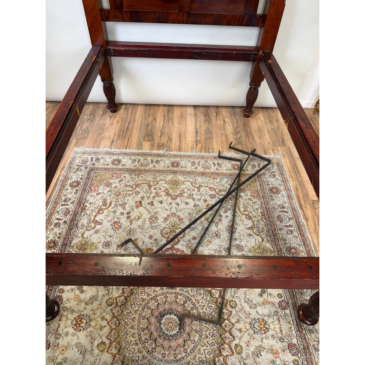 An American Classical Carved Mahogany Four-Poster Tester Bed, Possibly New York, circa 1825–1840, shown disassembled on a patterned rug with carved posts and metal support brackets resting across the rails.