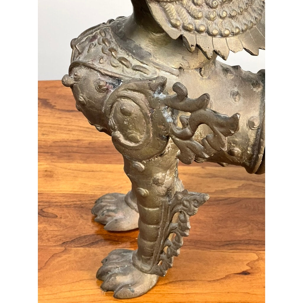 Close-up of a Vintage 17” Cast Brass Pixiu Tibetan Lion c. 1960 shows two ornate, clawed legs resting on wood—intricate designs and a weathered finish evoke classic Tibetan Chinese decor. Brand unknown.