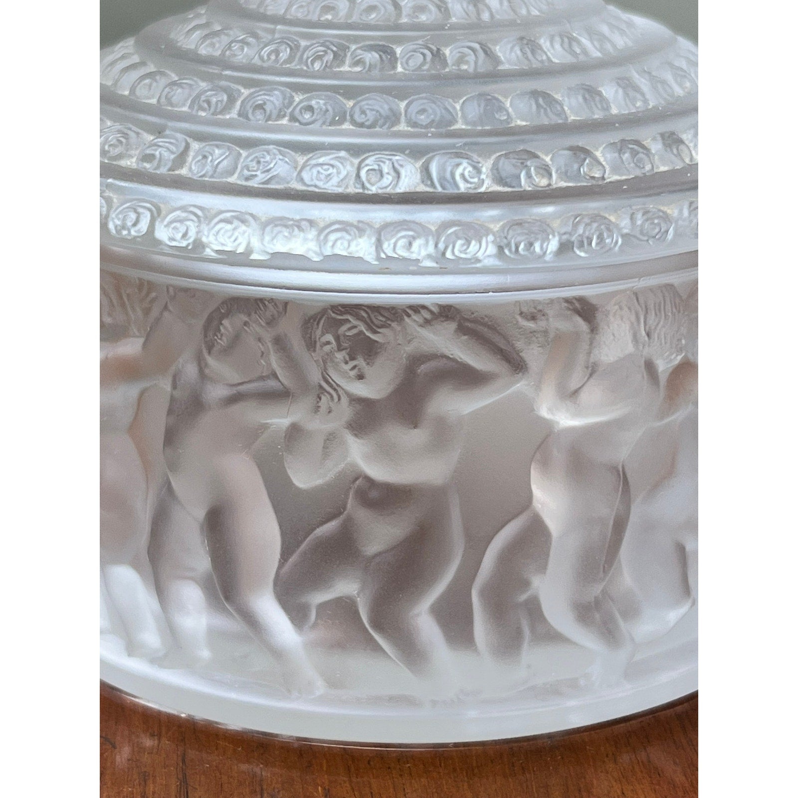 The Vintage Lalique Crystal Enfants Box by Lalique features frosted glass in the French art glass style, with classical reliefs of dancing nude figures encircling a round container and a decorative, textured lid.