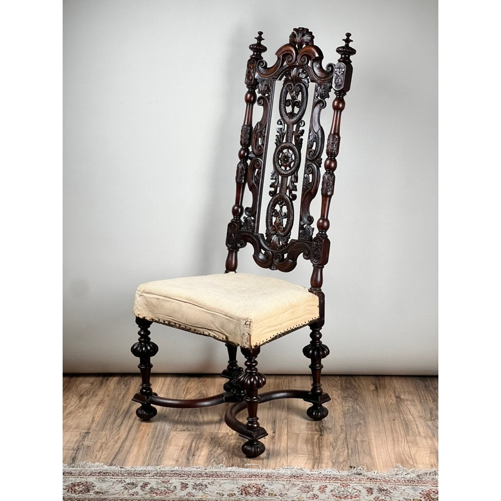 An Antique Fine Carved Flemish Side Chair, attributed to Daniel Marot c. late 17th century, features ornate carved details on the high backrest and legs with a cream upholstered seat. The chair is shown on a wooden floor beside a patterned rug.