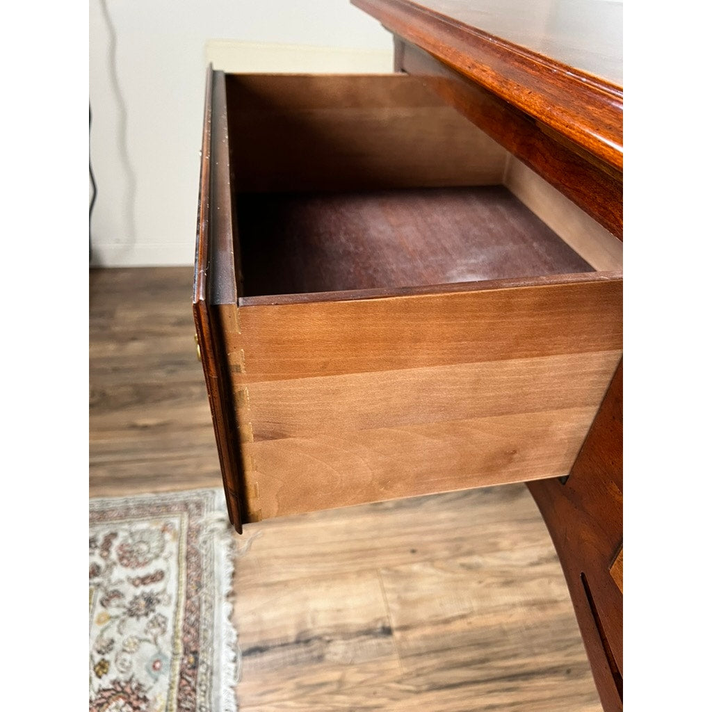An open, empty desk drawer with dovetail joints and a brown finish sits on a wood floor beside a patterned rug and a Vintage Solid Cherry Queen Anne Style Sideboard by Henredon against a white wall.