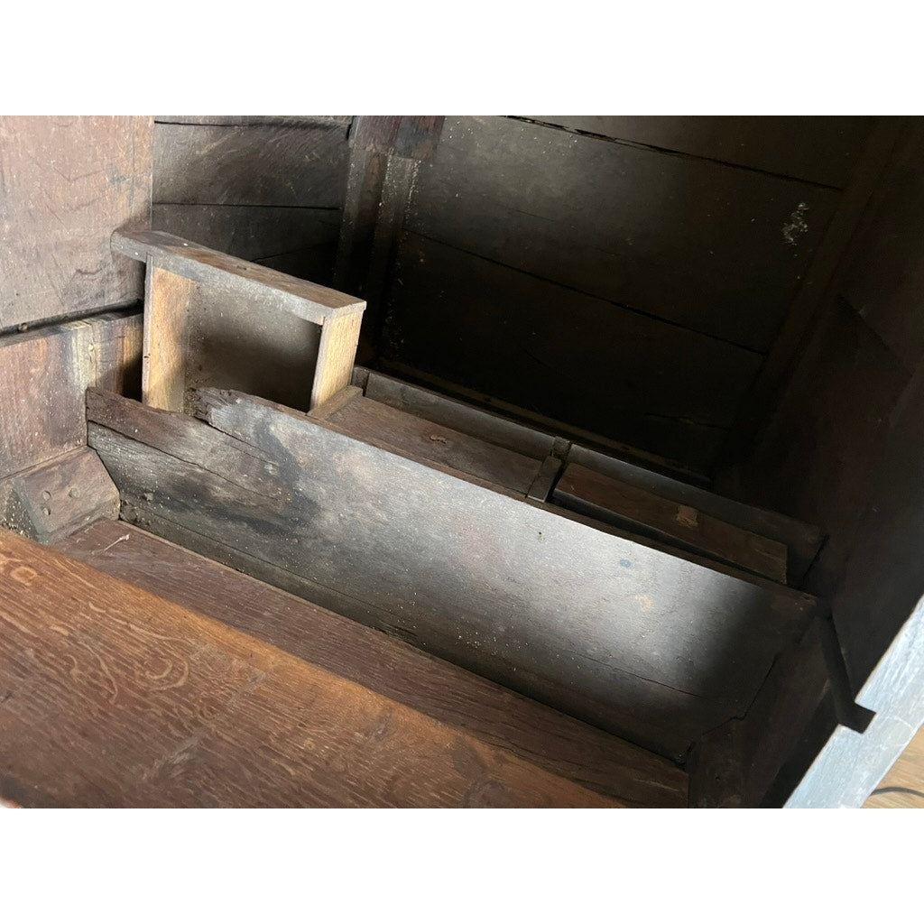 Close-up of the interior of an antique 18th-century Charles II style mule chest, possibly Irish or Scottish, showing dark, aged wood, a small divider for secret drawers, and a rustic, worn surface. Brand unknown.