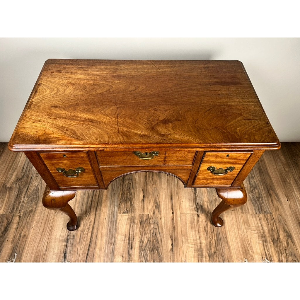 An Antique George III Queen Anne Mahogany Lowboy c. Late 18th Century, with three drawers and brass handles, stands on curved legs atop a wooden floor against a plain light-colored wall. Brand: Unknown.