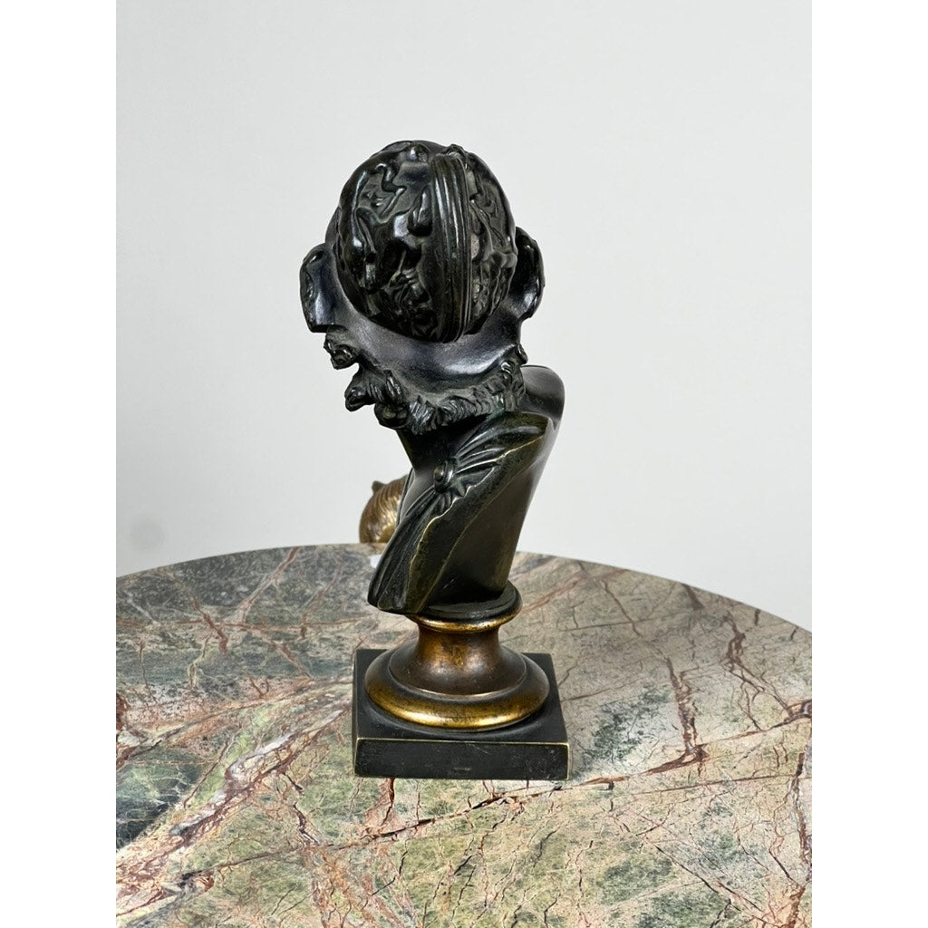An Antique Small Bronze Bust of King Menelaus, late 19th century, with detailed beard and flowing hair, is displayed on a pedestal base atop marble against a plain light background. Brand: None/Unknown.