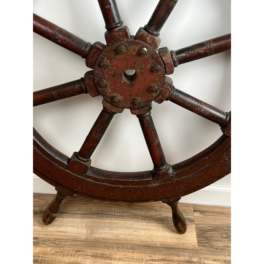 A close-up of the Antique Eight Spoke Mahogany and Iron Ship’s Wheel stamped “1864 US,” featuring a weathered reddish-brown finish—an ideal piece to bring authentic 19th-century maritime charm to your space.