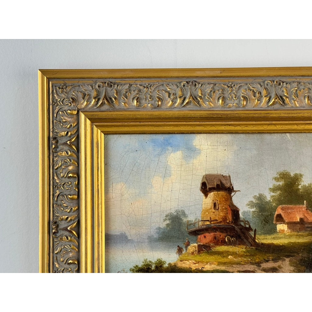 Close-up of the ornate gold corner of an Antique Continental School Oil on Canvas Landscape with Windmill, signed “Brüguer,” circa 1880-1910, showing part of a scenic view with water, figures, trees, and houses under a blue sky.