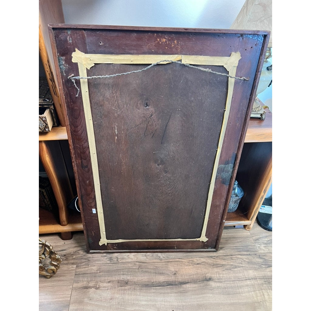 The back of an American Federal Mahogany Wall Mirror with Fan Inlay, Original Hand Silvered Glass, Circa 1810–1825, features yellowed tape along its edges and a hanging wire attached, evoking its early nineteenth-century origins. The mirror's frame is pictured leaning against a wooden shelf on a wood-patterned floor.