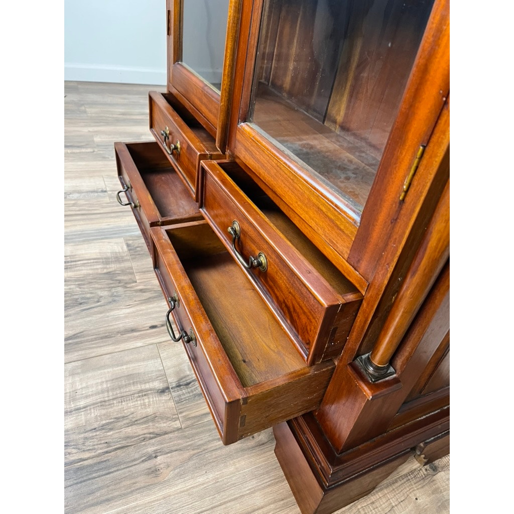 A close-up of a Vintage Victorian Style Glass Door Mahogany Bookcase with three open drawers featuring metal handles, set on a light wood floor. Brand: None and/or Unknown.