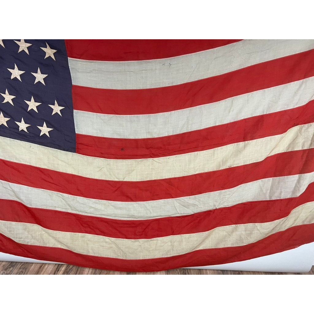 A close-up of an Antique 45 Star American Flag from the Spanish American War era (9’9 x 6) with visible wrinkles and slight discoloration, showing stars on blue and red and white stripes, displayed on a wooden floor. Brand: Unknown.