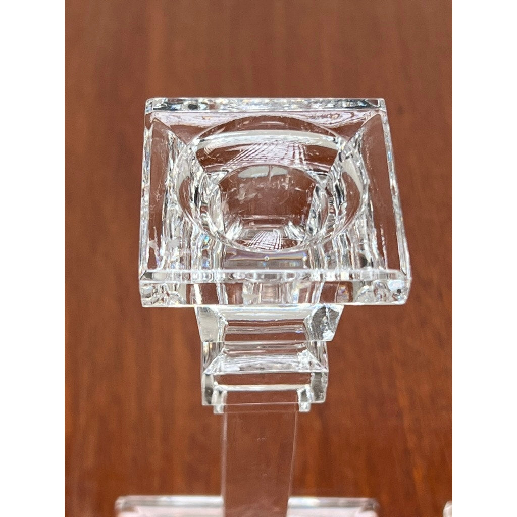A close-up of a Vintage Pair Tiffany & Co. Clear Crystal Candlesticks with square tops, geometric design, and reflective finish, placed on wood—evoking the classic elegance of Tiffany & Co. craftsmanship.