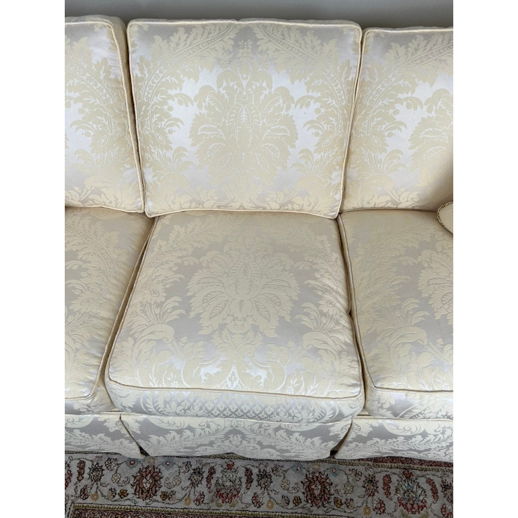 The Stickley Vintage Custom Ivory Upholstered Sofa features three seat and matching back cushions in an ornate damask pattern. An elegant, patterned rug edge appears below, highlighting this sophisticated custom-made piece by Stickley.
