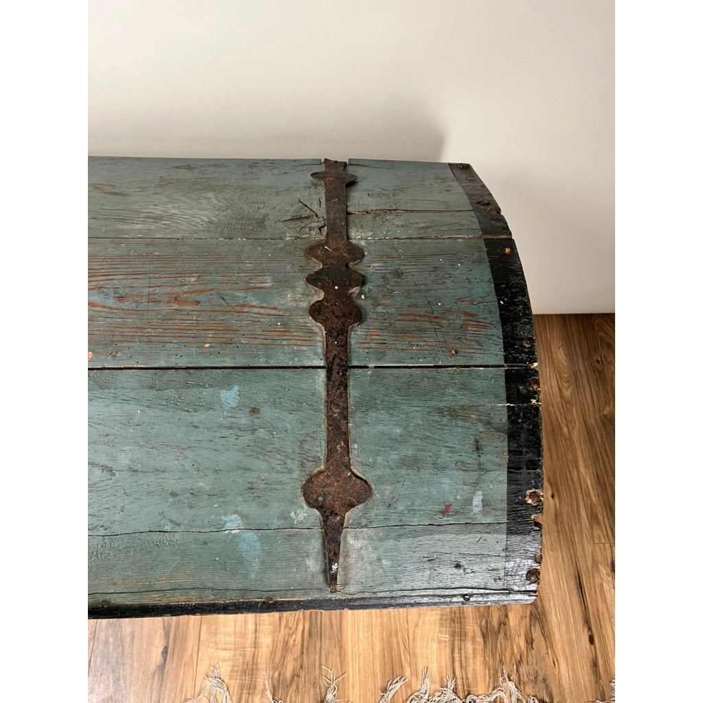 The Antique Swedish Oak Kista Dowry Chest c. 1841, with its weathered oak, faded blue-green paint, and large rusty hinge, sits on a wood floor as a fringed rug peeks out—echoing the rustic charm of Swedish folk art.