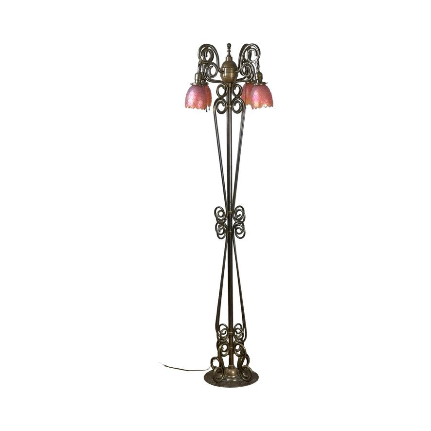 Antique Art Nouveau brass floor lamp, attributed to Jules Cayette and Charles Schneider c. 1920, with intricate scrollwork, three curved arms holding pink flower-shaped glass shades, and a round base with visible cord. Brand: Unknown.