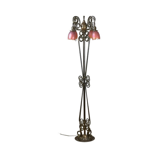 Antique Art Nouveau brass floor lamp, attributed to Jules Cayette and Charles Schneider c. 1920, with intricate scrollwork, three curved arms holding pink flower-shaped glass shades, and a round base with visible cord. Brand: Unknown.