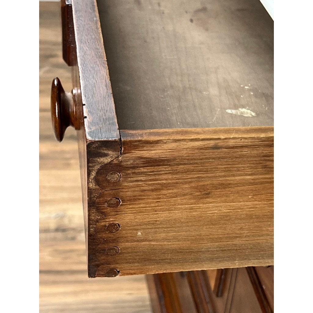 A close-up of a partially open drawer on the Antique Victorian Marble Top Four Drawer Chest c. 1910 reveals dovetail joints and a round wooden knob, with its warm brown finish and surface wear showcasing timeless character.