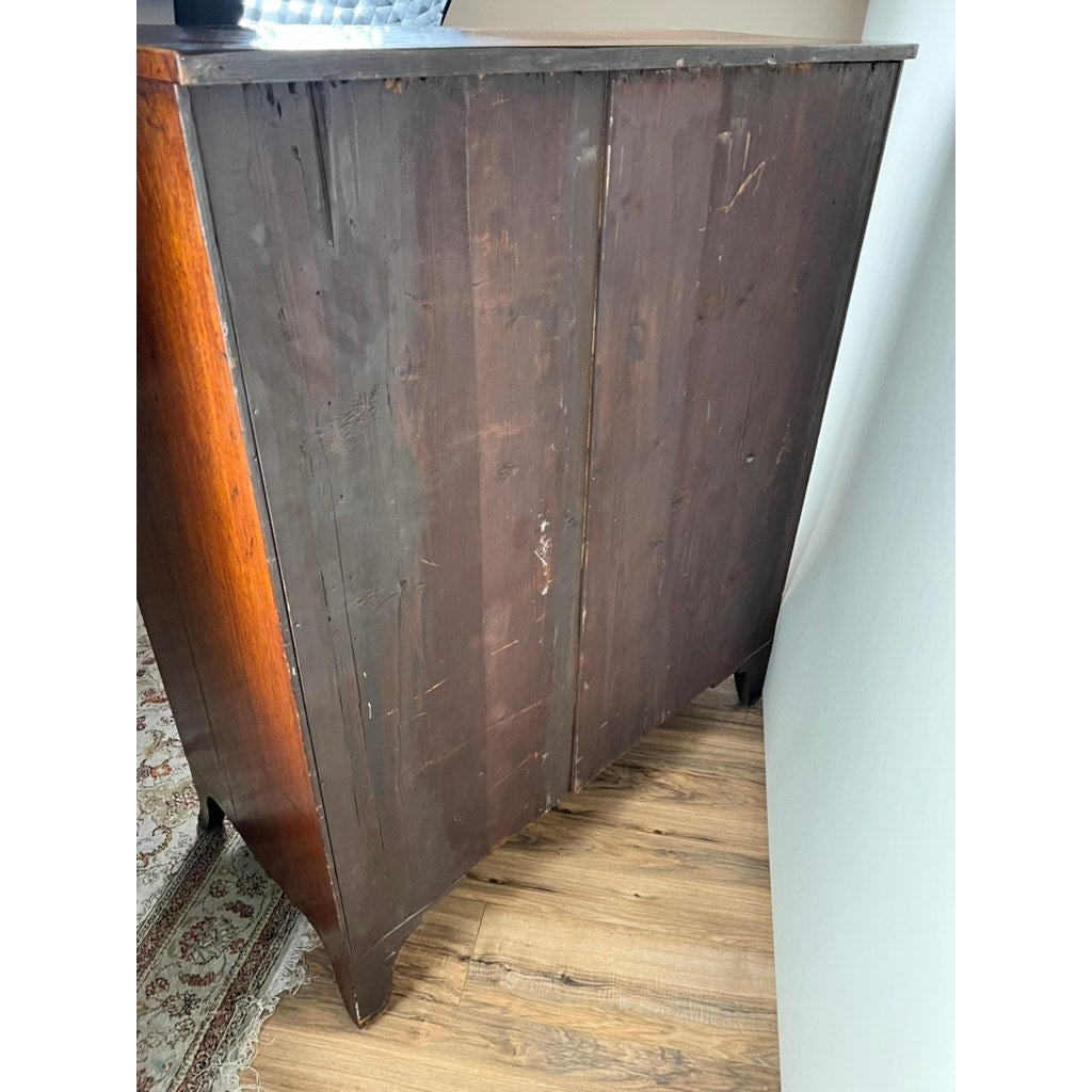 An Antique George III Two Over Four Chest with French Feet, c. early 19th century, featuring a dark, worn finish and visible scratches, stands on a hardwood floor near a white wall and patterned rug. Its side appears faded and scuffed.