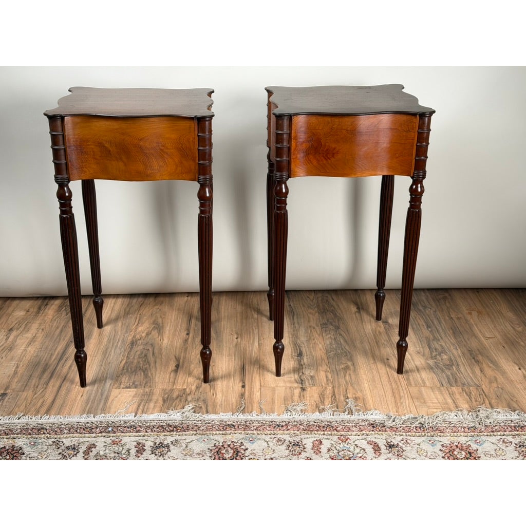 A pair of American Classical Revival Mahogany Two-Drawer Work Tables, circa 1880–1910, featuring two drawers each, scalloped tabletops, and slender, fluted legs.