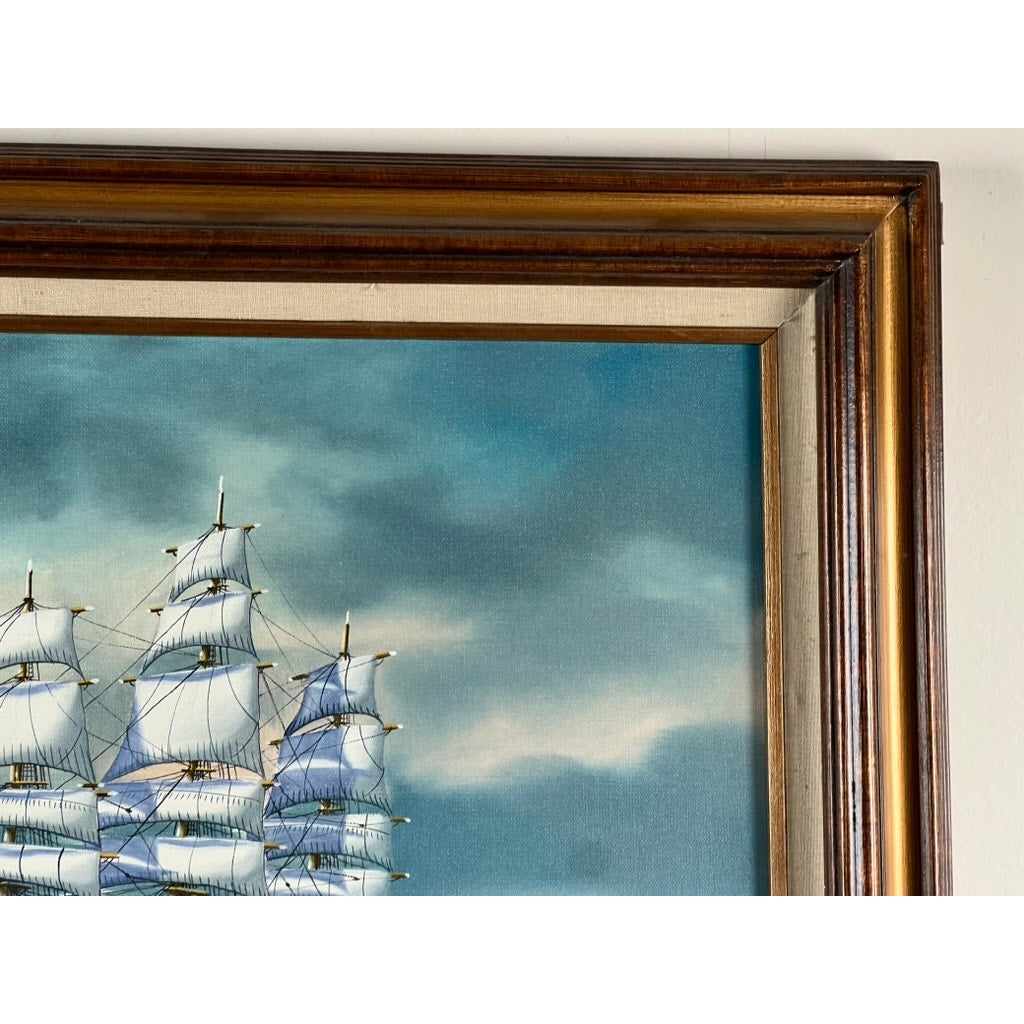 Close-up of “Tall Ship Under Sail” oil on canvas by John Richard Perry ME 1984, showing the top section of a sailing vessel with white sails against a blue sky, and part of the wooden frame on the right and top edges.