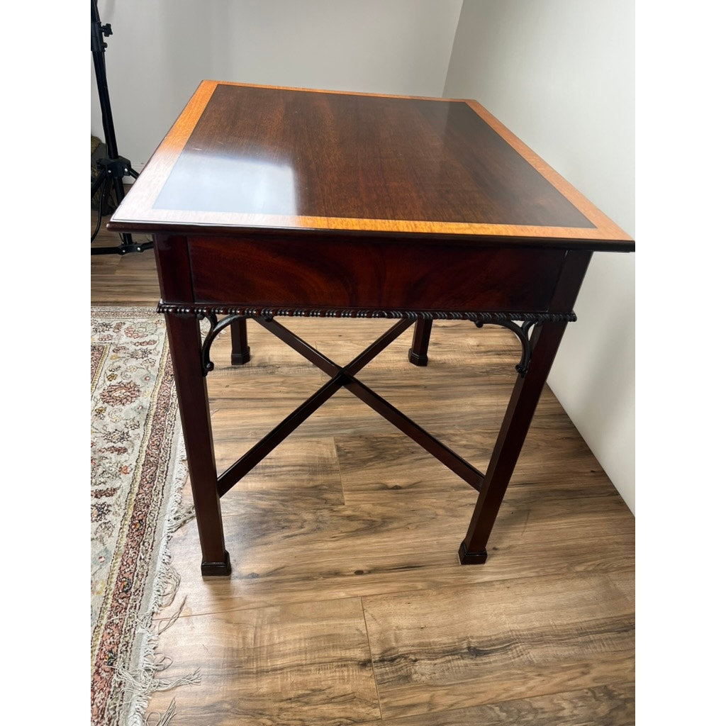 The Vintage Federal Style X Stretcher One Drawer End Table by Stickley features detailed edges and crossed supports, shown on a wooden floor near a patterned rug and white walls.