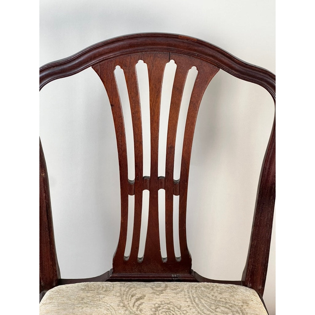 Close-up of an Antique English George III Mahogany Hepplewhite Armchair (early 19th c.) showing its elegant, arched top with four vertical slats and a seat upholstered in light-colored patterned fabric. Brand unknown.