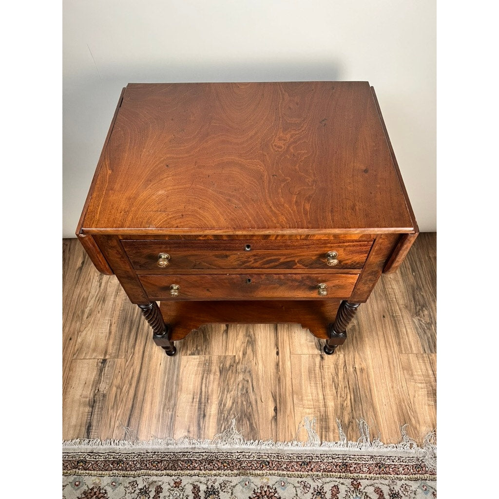 A top-down view of an Antique Federal Mahogany Two Drawer Work Stand with lion’s head pulls c. 1820, standing on a wood floor beside the edge of a patterned rug. Brand: Unknown.