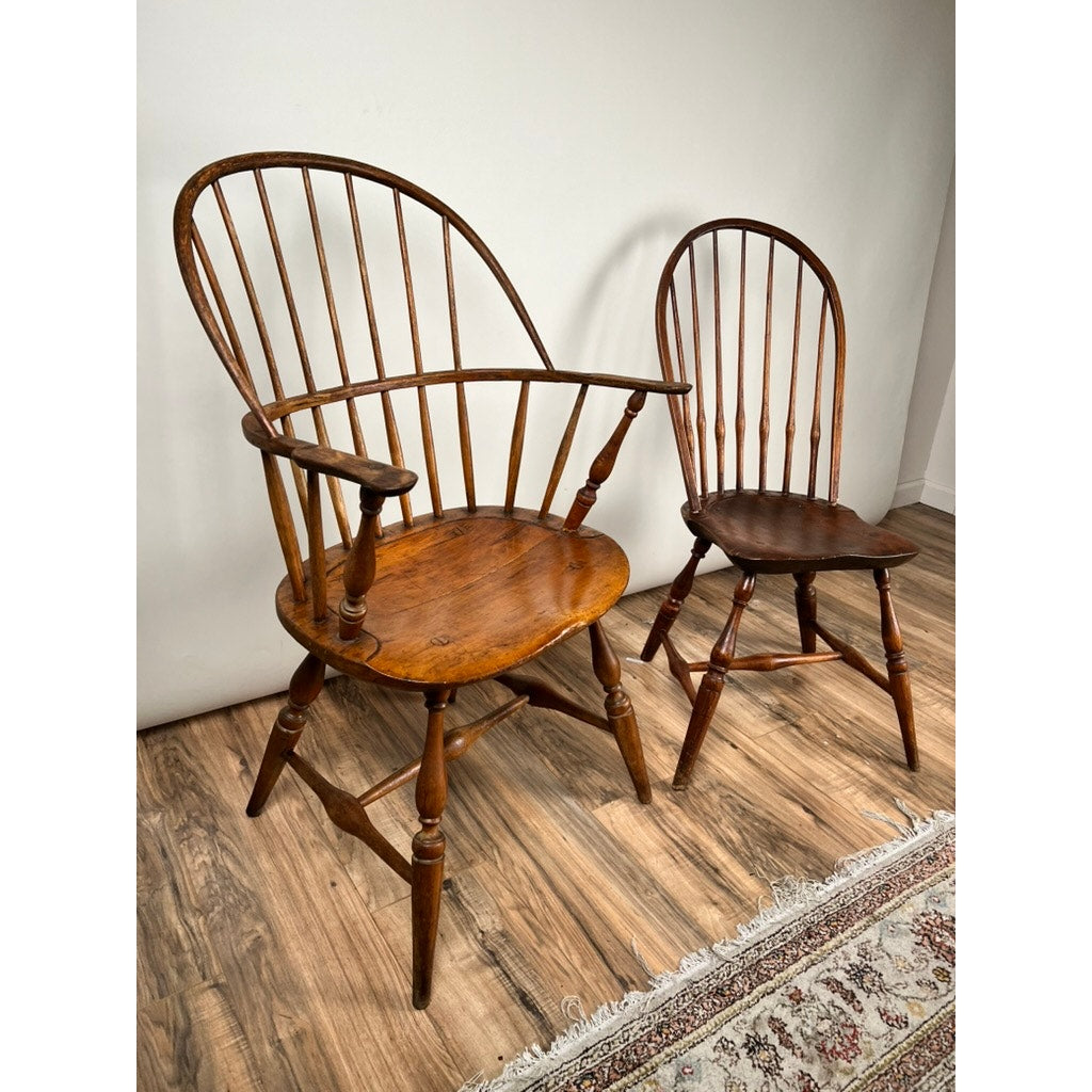 The Antique Near Pair 18th Century Windsor Chairs features one high-back chair with armrests and a smaller armless chair, both showcasing classic spindled backs and rustic early American craftsmanship.