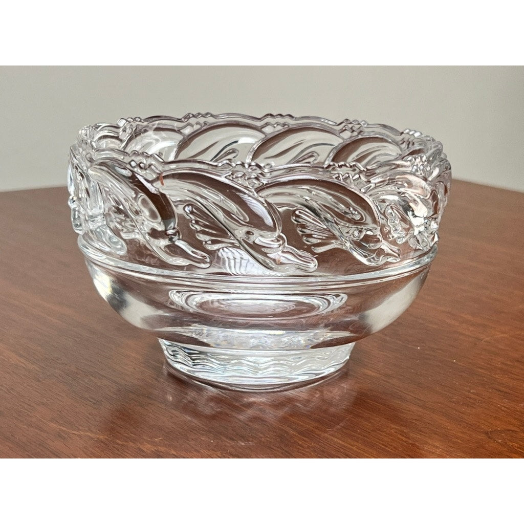 A Vintage Tiffany & Co. Mid-Century Modern Crystal Dolphin Pattern Footed Bowl by Tiffany & Co., displayed on a wooden surface.