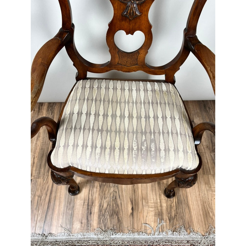 An Antique George III Mahogany Open Arm Chair (late 18th century) with curved arms and carved backrest rests on a wood floor. Its seat is upholstered in cream fabric with a vertical teardrop pattern, next to a fringed rug. Brand: Unknown.