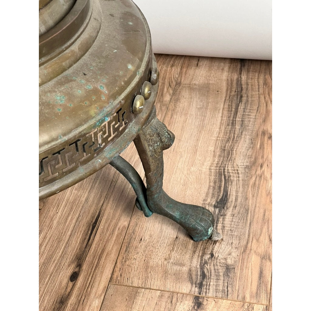 Close-up of an Antique Venetian Brass Bell Room Heater Brazier (19th Century) with decorative patterns, claw-shaped foot, and green patina on metal, highlighting its age. Brand unknown. Resting on a wooden floor.