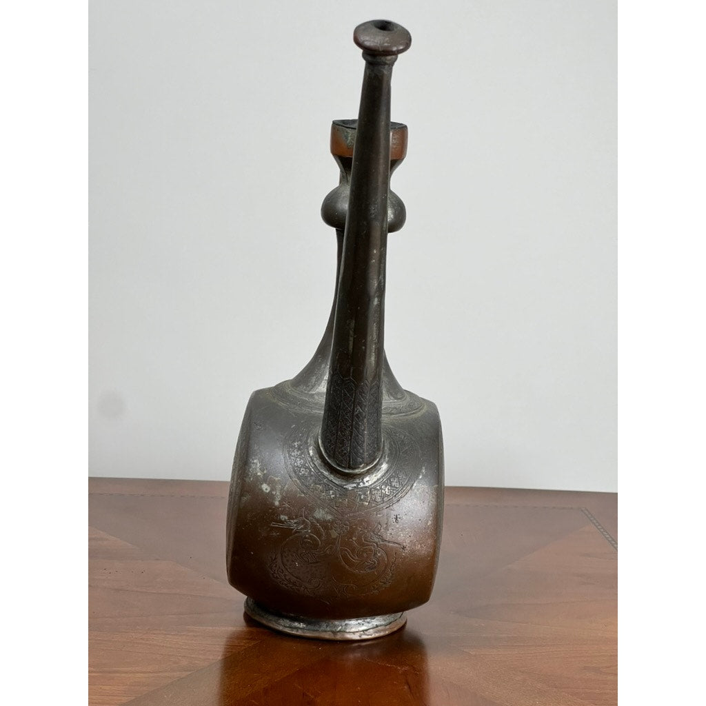 An Antique Qajar Persian Copper Engraved Ewer, 19th Century, with a rounded base and long spout, is displayed on wood against a plain light background. Brand: Unknown.