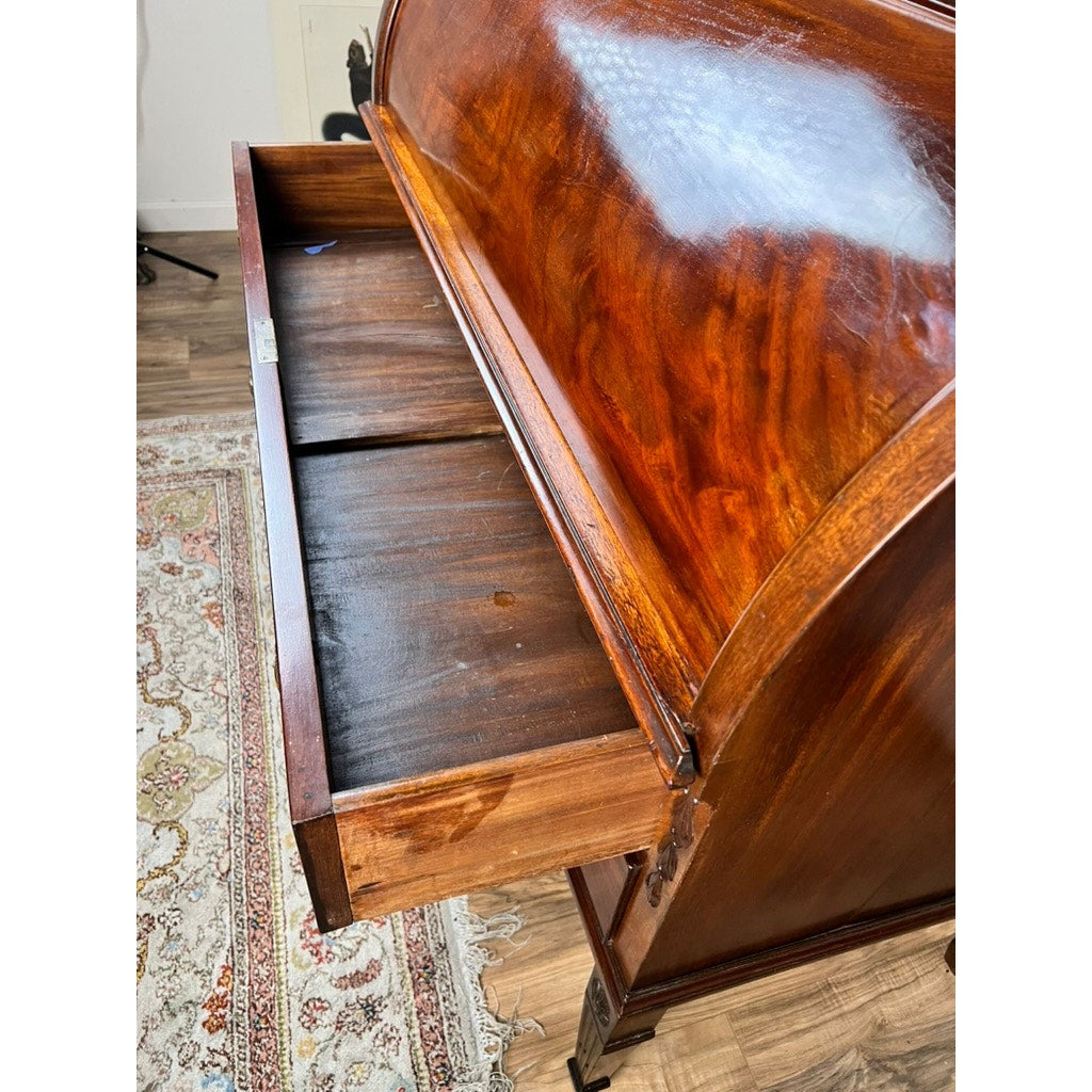 An Antique Directoire Style French Cylinder Desk with Slate Top c. Late 19th Century, featuring a rich brown finish and an open drawer, stands on a patterned rug atop a wooden floor, embodying elegant neoclassical mahogany design.
