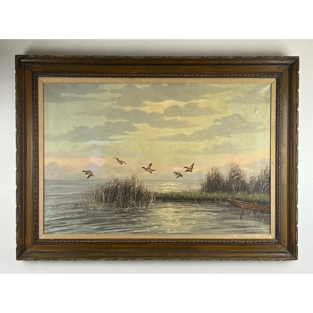 Painting Oil on Canvas 'Mallards Over Marsh' by Joseph Glotzer depicts mallards flying over a lake at sunset, with reeds and a partially visible boat at the water’s edge, beneath a sky filled with soft clouds.