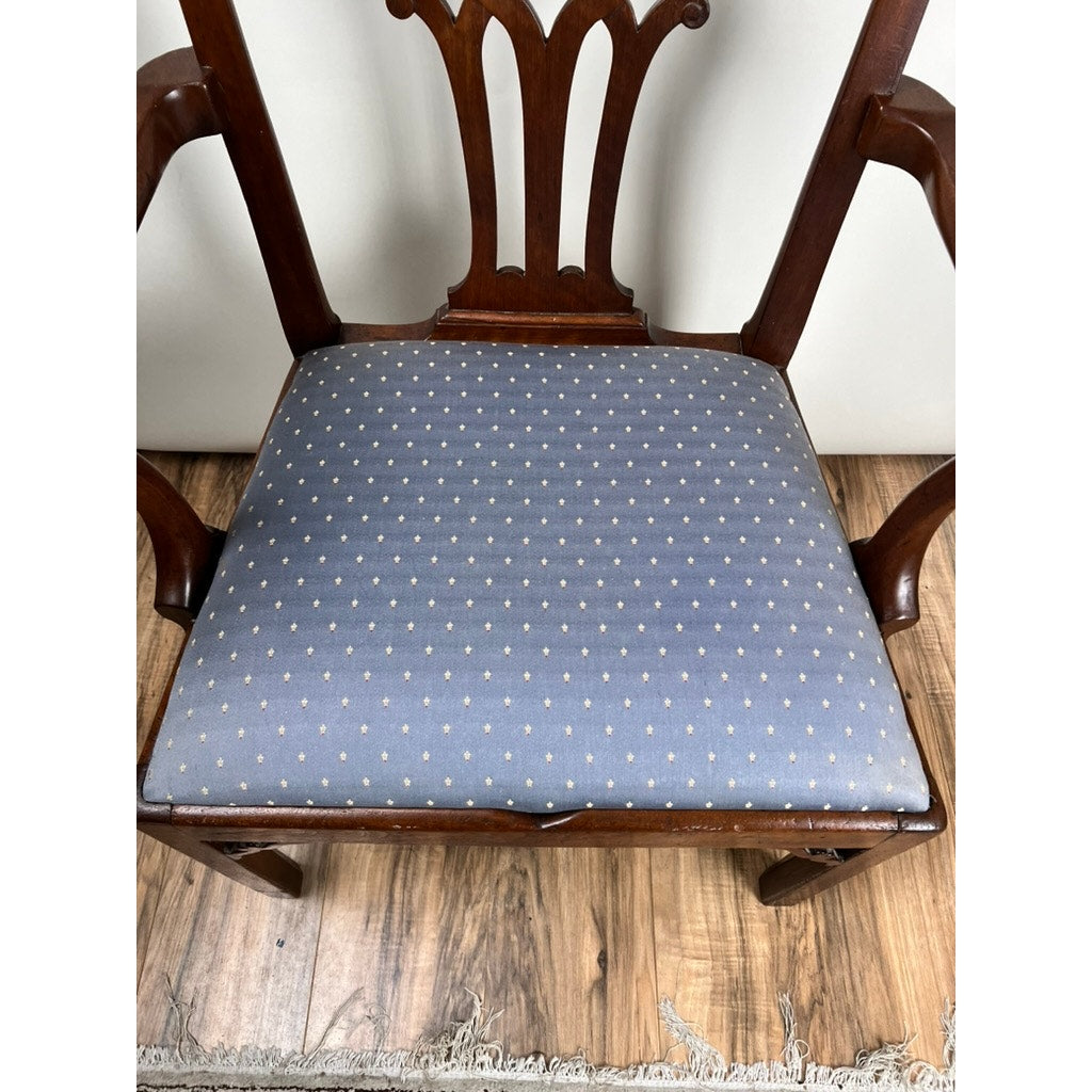 The Antique Chippendale Walnut Open Arm Chair c. Late 18th Century, with an ornate backrest and blue seat cushion with white dots, brings classic English charm to the room when placed on a wood floor near a fringed rug.