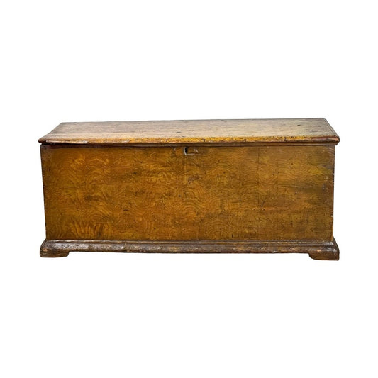 An Antique 18th Century Grain Painted Pine Six Board Blanket Box in mustard with till, featuring a rectangular shape, flat lid, rustic worn finish, and short sturdy feet, stands against a plain white background.