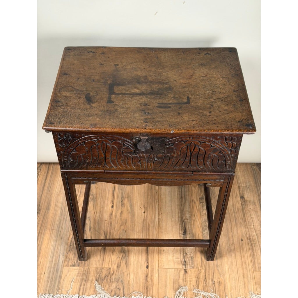 English Jacobean Carved Oak Bible Box on Later Stand, c. Late 17th Century, featuring an antique oak box with a carved front panel resting on a tall wooden stand.