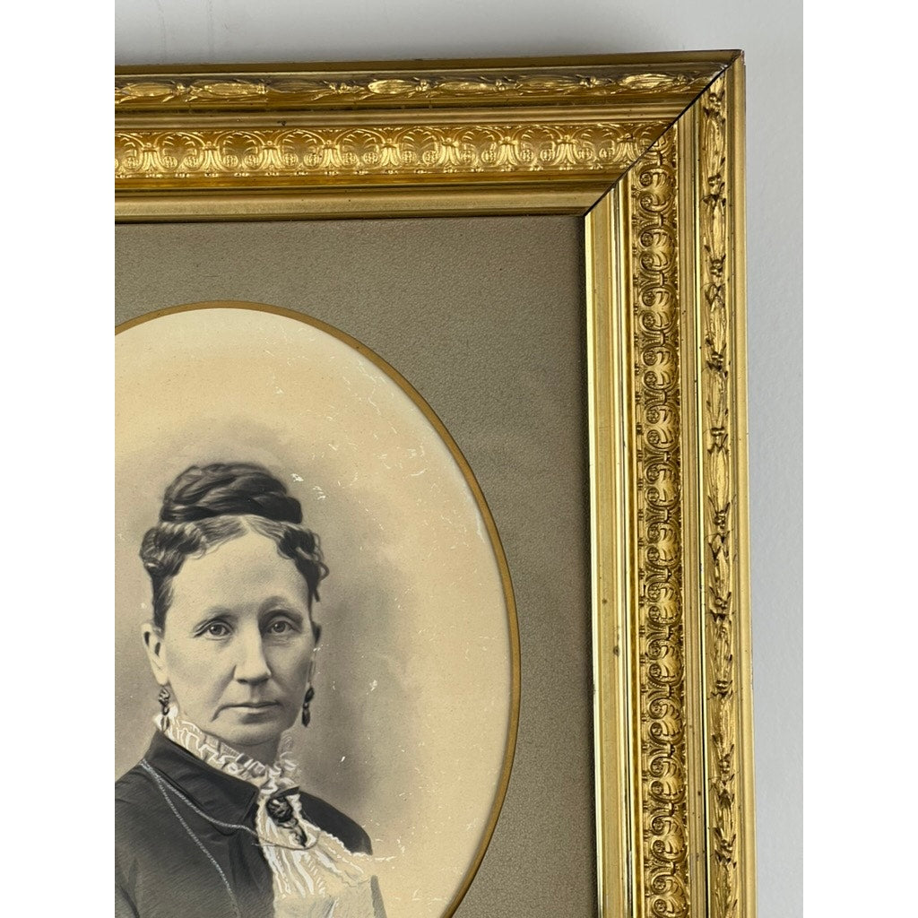 An Antique Civil War Era Portrait of a Woman in a gilt wood frame, featuring floral details, is shown partially visible against a neutral wall. Brand: None/Unknown.